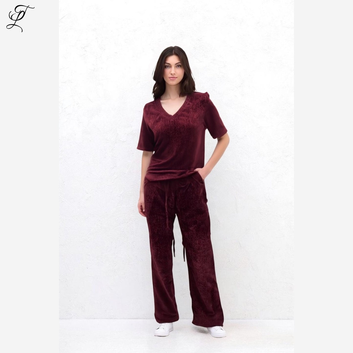 Model draagt de bordeauxrode Chastar Fluwelen Top met V-hals en korte mouwen voor een luxe en comfortabele look.