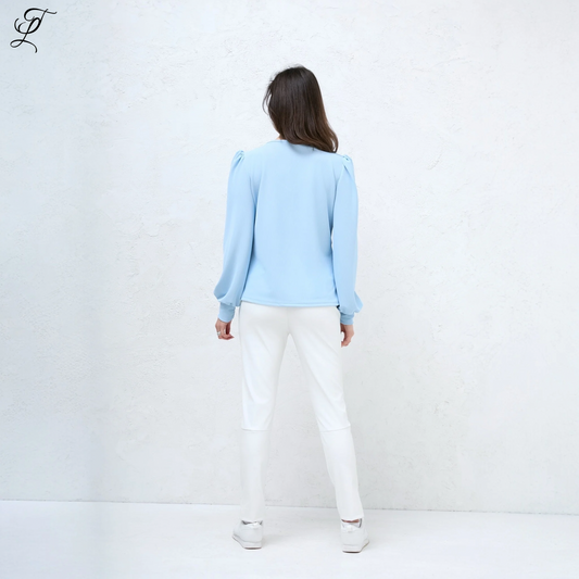 Chastar V-Hals Blouse getoond vanaf de achterkant, gedragen met witte broek. Lichtblauwe blouse met elegante pofmouwen en soepelvallende pasvorm. Stijlvolle casual look tegen witte achtergrond. Blouses, Collectie