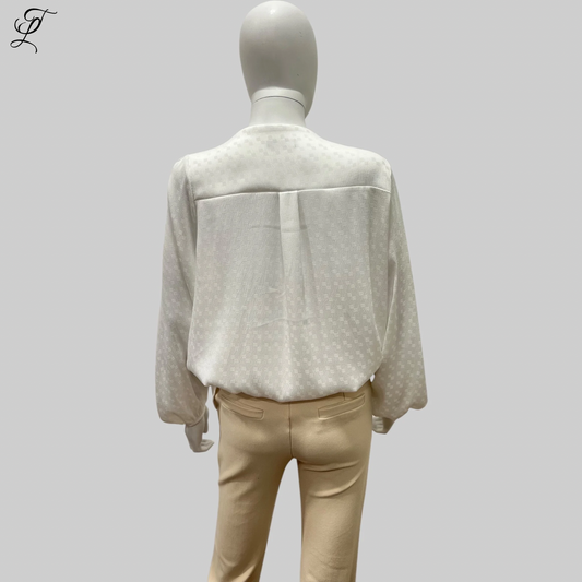 Chastar V-Hals Blouse getoond op een paspop, achterzijde weergave met subtiel ingeweven patroon in off-white. Elegante loose-fit stijl met lange mouwen en elastische manchetten, gecombineerd met een beige broek. Blouses, Collectie