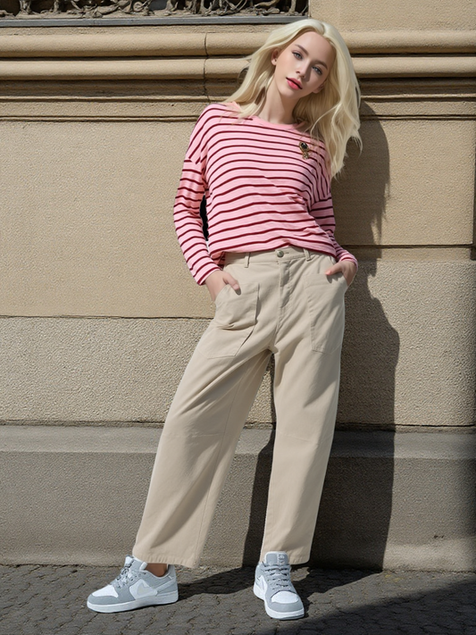 vrouw draagt oversized lange mouw t-shirt roze met rode strepen gecombineerd met beige broek en grijze sneakers