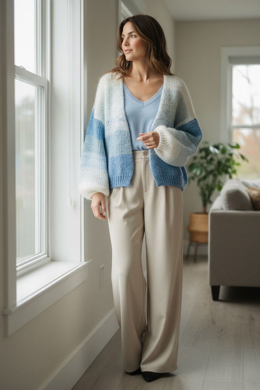 Dames draagt nieuw vest van zacht gebreid materiaal in blauw-wit, gecombineerd met lichte broek in lichte kameromgeving.