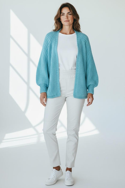 Dame draagt lichtblauwe gebreide vest uit Nieuw collectie van Chastar in lichte, moderne setting.