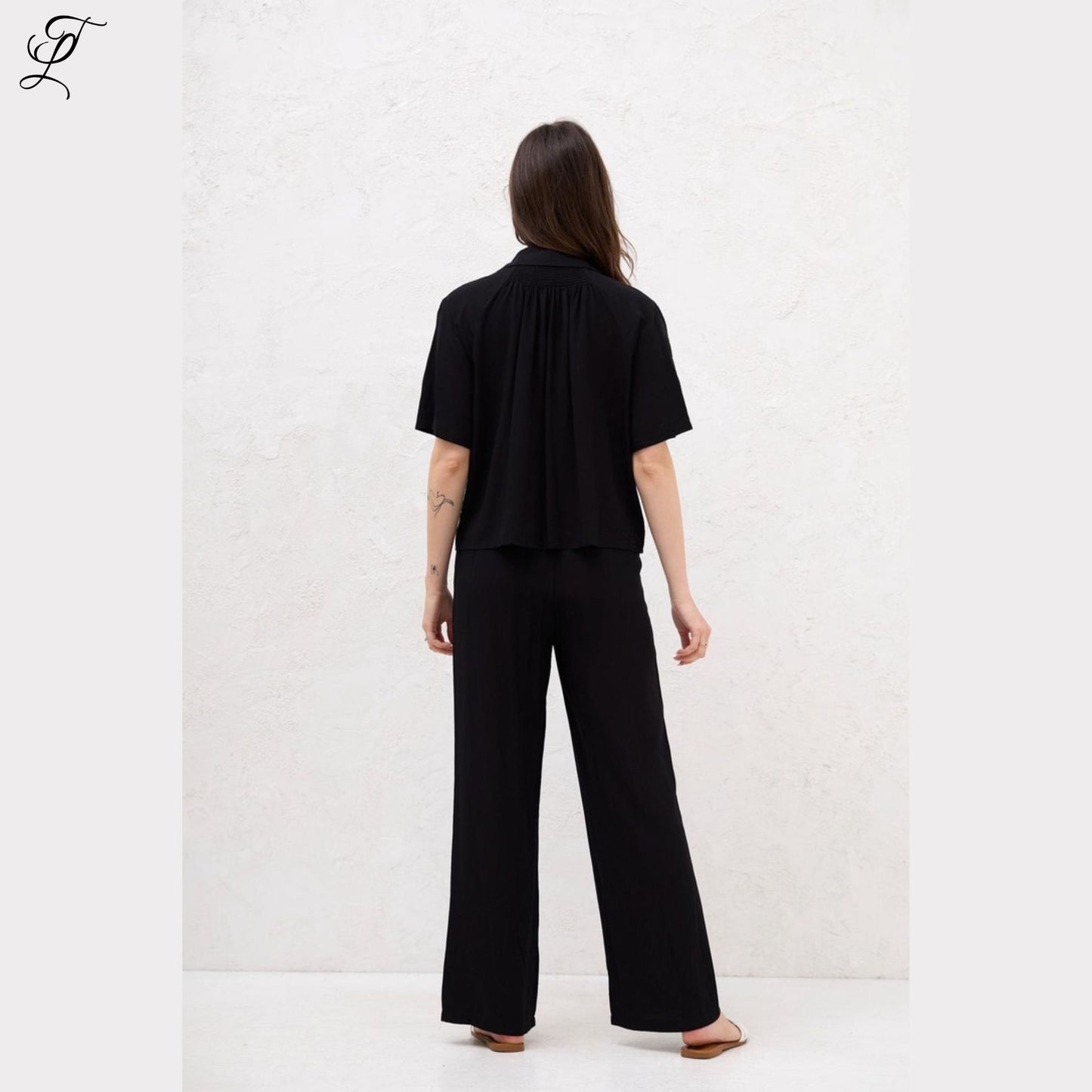 Model draagt de Chastar Korte Mouwen Blouse in zwart, stijlvol en comfortabel met relaxte pasvorm.