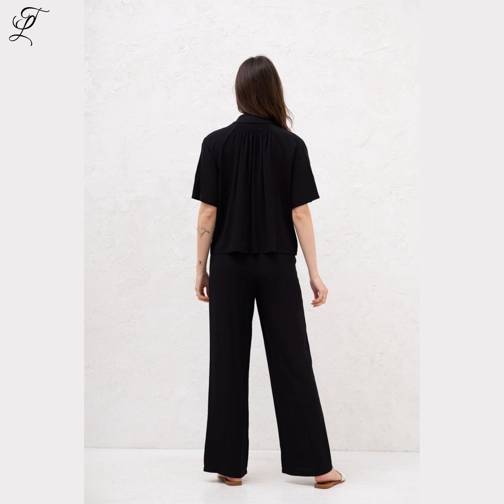 Model draagt de Chastar Korte Mouwen Blouse in zwart, stijlvol en comfortabel met relaxte pasvorm.