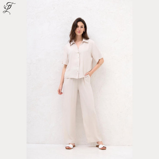 Vrouw draagt lichte, luchtige Chastar Korte Mouwen Blouse met parelmoerknopen voor een relaxte, stijlvolle look.