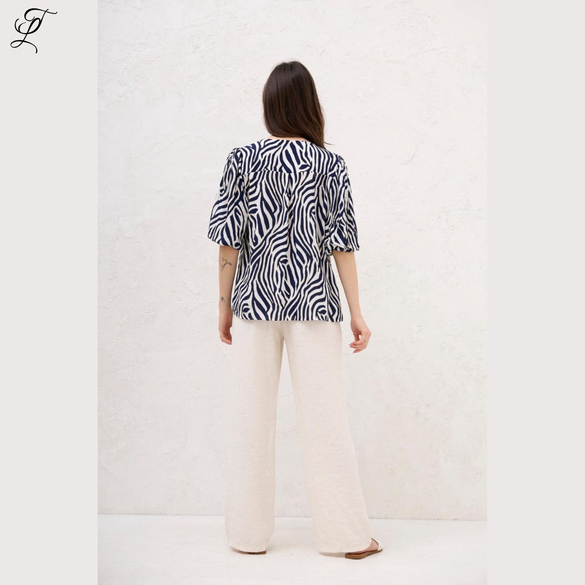 Achteraanzicht van vrouw die Chastar Viscose Blouse Zebra Print draagt met elegante pofmouwen en losse fit.