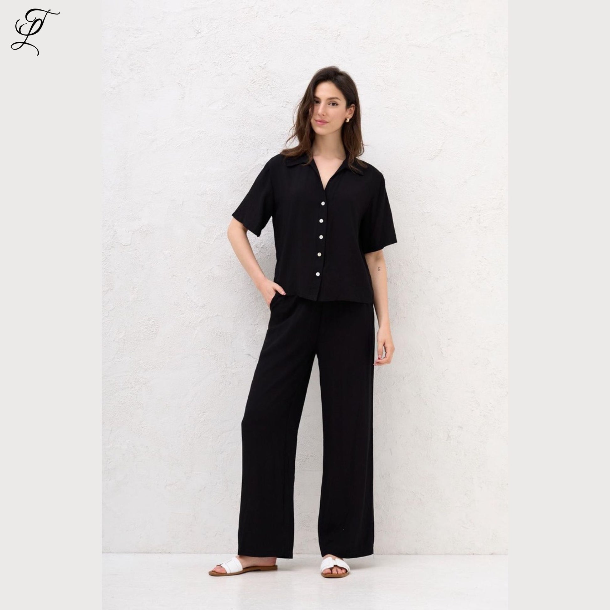 Vrouw draagt comfortabele zwarte Chastar Korte Mouwen Blouse met parelmoerknopen, stijlvol en perfect voor zomerse dagen.