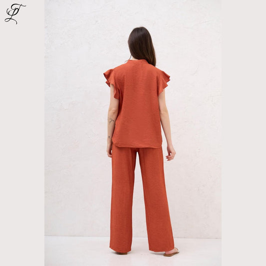 Achteraanzicht van vrouw in roestkleurige Chastar Linnen Blouse met korte ruffle-mouwen, perfect voor een zomerse dag.