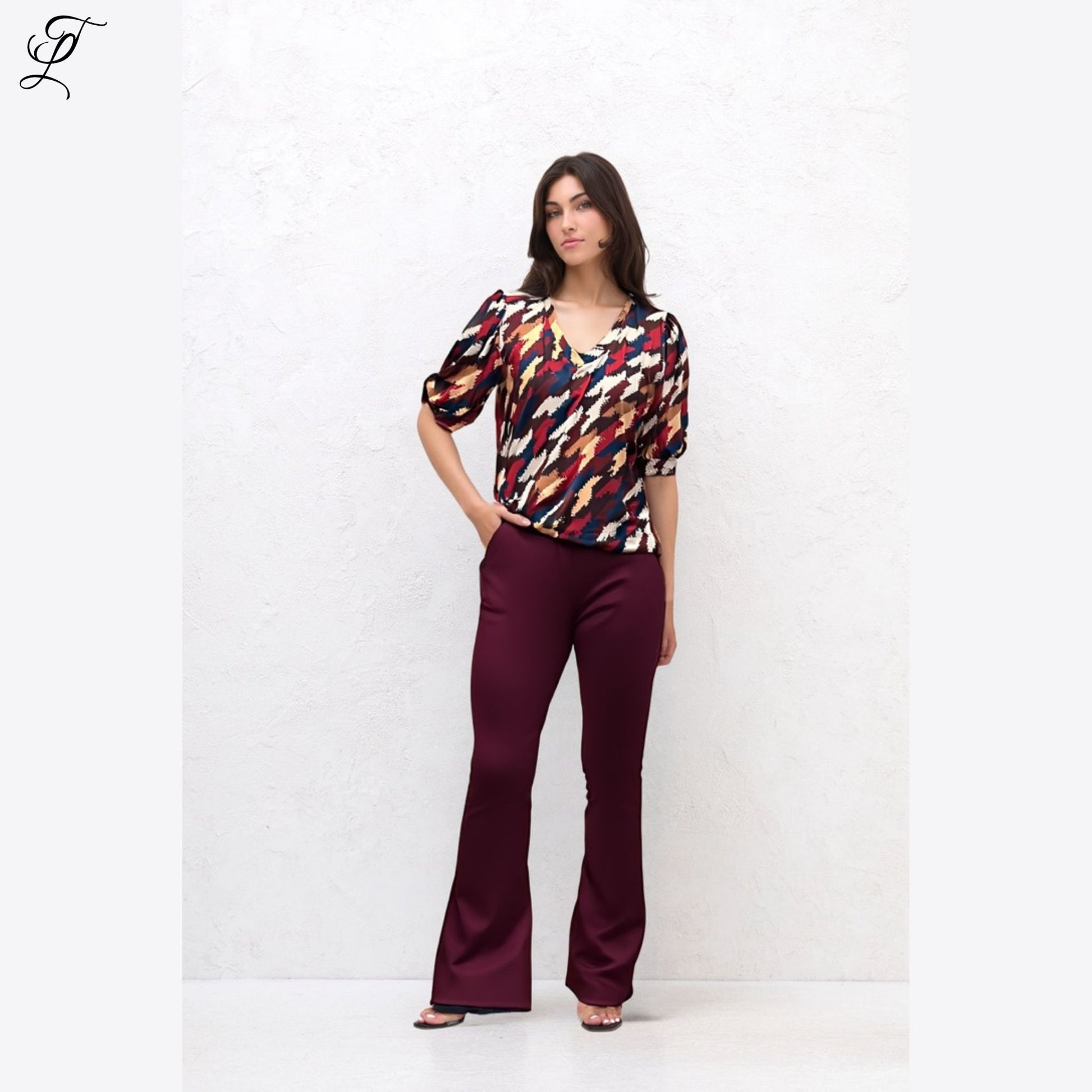 Damesmodel draagt Chastar Soft Top Mila met opvallende print en pofmouwen, gecombineerd met bordeaux broek uit zomercollectie.