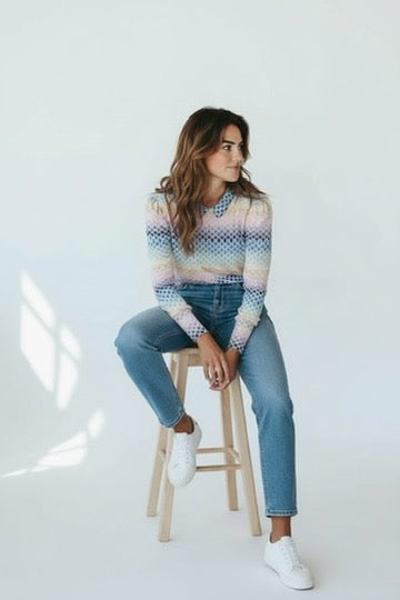 Vrouw zit op kruk met zacht en stretchend Soft Top truitje in maat S/M met lichte pasteltinten en jeans