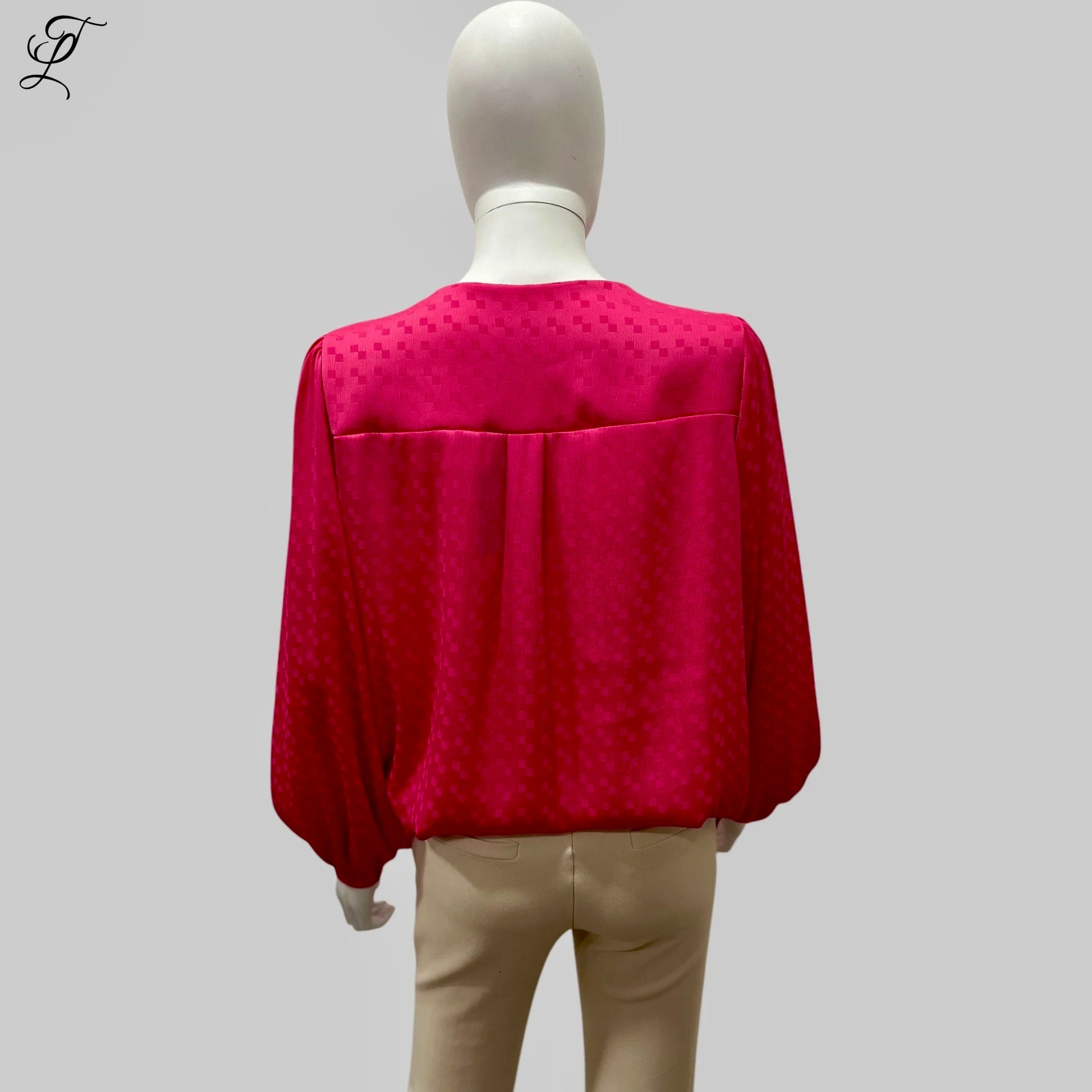 Chastar V-Hals Blouse in levendig fuchsia roze, gefotografeerd op een mannequin van achteren. De blouse toont een luchtige pasvorm met lange mouwen en elastische boorden, gemaakt van soepelvallende stof met subtiel ingeweven patroon. Collectie Blouses.