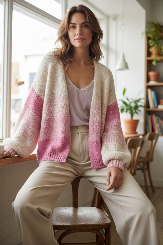 Vrouw draagt nieuw gebreide vest in creme en roze tinten uit Chastar collectie, gecombineerd met beige broek.