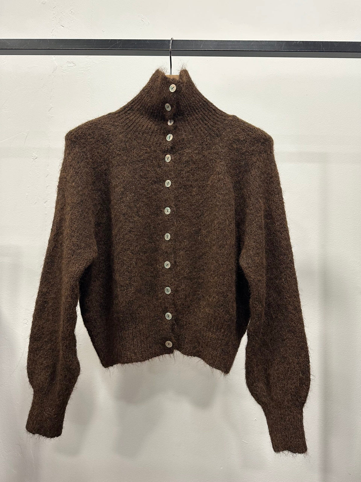 Chastar Cardigan Gebreid met hoge kraag in choco bruin met knoopsluiting en geribde boorden, aan een kledinghanger.