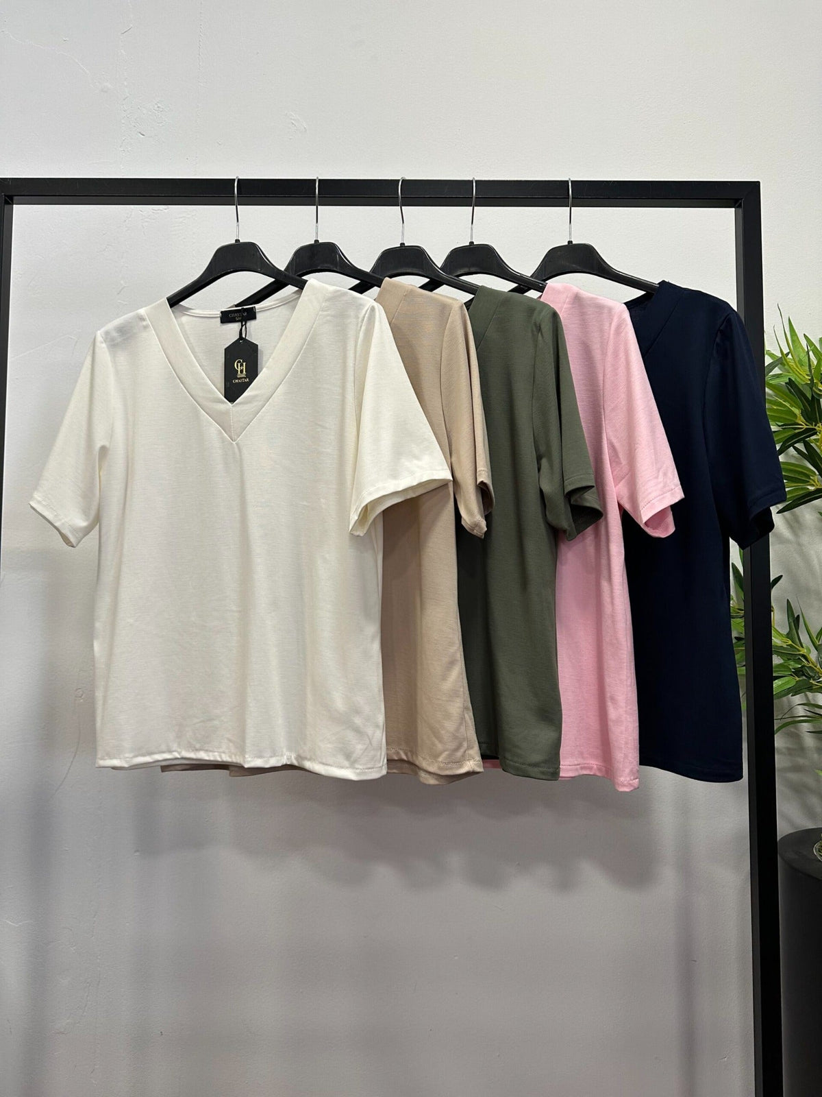 Chastar uni tops met V-hals en korte mouwen in meerdere kleuren, getoond aan kledinghangers