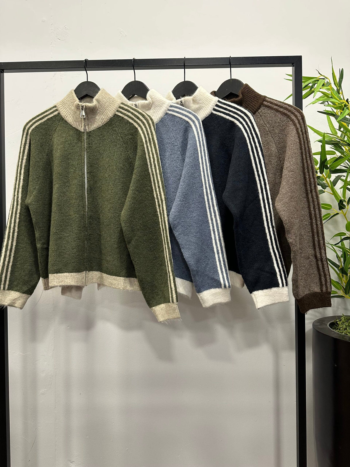 Chastar Vest met contraststrepen in army groen, licht blauw, donker blauw en bruin met hoge kraag, aan een kledingrek.