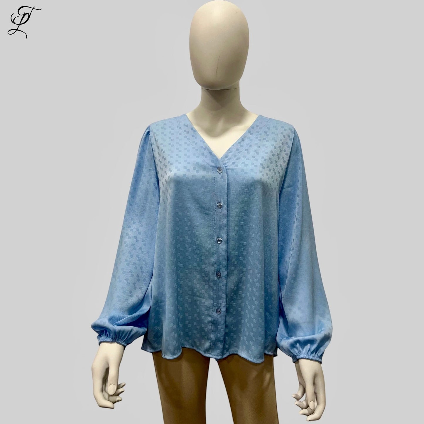 Trendy Leslie light blue V-neck blouse with subtle square pattern and button-up front. Long sleeves with elastic cuffs.